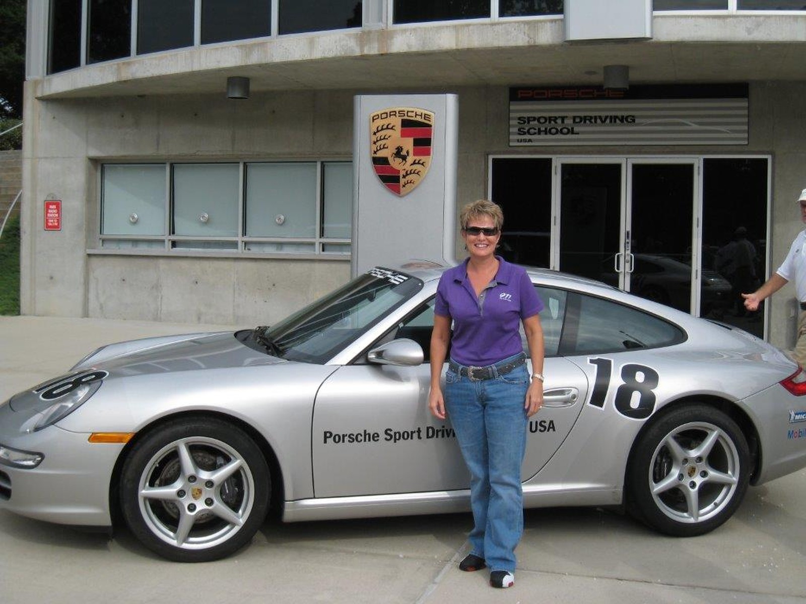 Jane Scaletta stands beside a Porsche Sport Driving School vehicle